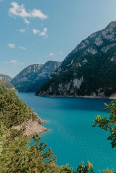 The concept of eco-tourism and active recreation. National Park. Mountain Emerald lake in the wooded mountains. Sunny day in autumn.