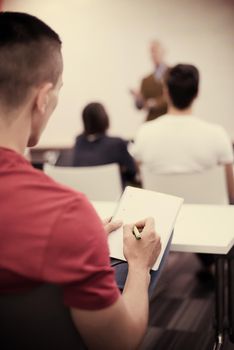 male student taking notes in classroom. business education concept, casual young businessman on seminar training