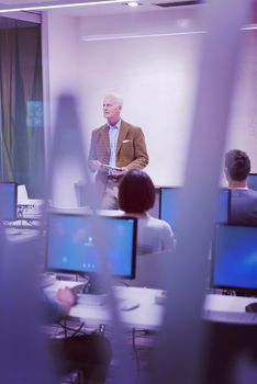 handsome mature teacher and students in computer lab classroom