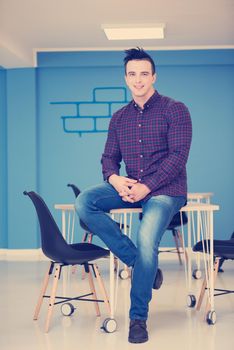 portrait of young business man in casual clothes sitting on table at  new startup office space
