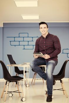 portrait of young business man in casual clothes sitting on table at  new startup office space