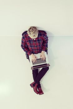 top view of young business woman working on laptop computer in modern bright startup office interior, sitting on floor