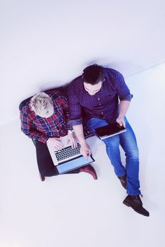 startup business and new mobile technology concept with  young couple in modern bright office interior working on laptop and tablet computer on new creative project and brainstorming, aerial top view