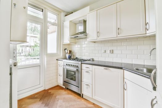 Interior of spacious light kitchen with modern white furniture in light apartment