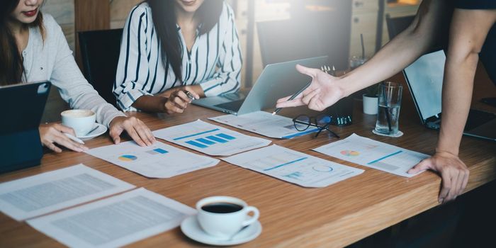 Business team working together and training to analyze technical price graph and indicator. Chart and stock trading in paperwork on desk.