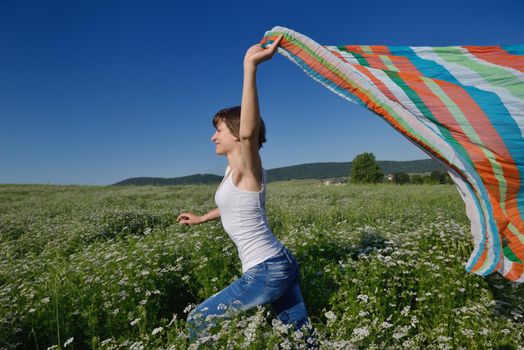 Young woman standing jumping and running  on a wheat field with blue sky in  background at summer day representing healthy life and agriculture concept