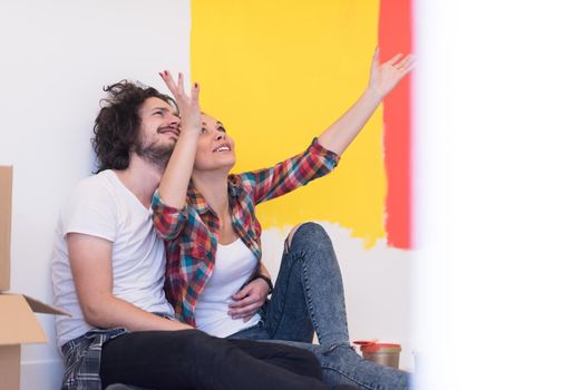 Happy young couple relaxing after painting a room in their new house on the floor