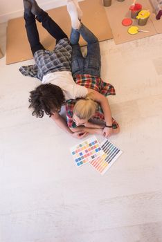 Happy young couple relaxing after painting a room in their new house on the floor