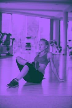 Cute young woman stretching and warming up for her training at a gym duo tone