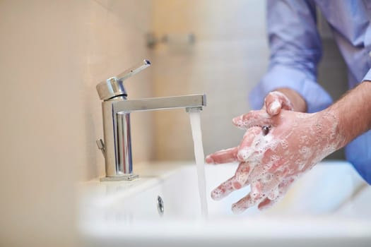 Coronavirus infection and spreading prevention, proper Washing hands with liquid soap. Hygiene male antibacterial hands water wash closeup in bathroom.