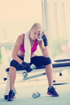 halethy young woman exercise with dumbells and relaxing on banch in fitness gym