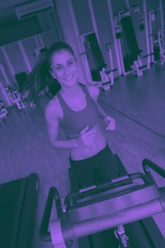 sport, fitness, lifestyle, technology and people concept - smiling woman exercising on treadmill in gym duo tone