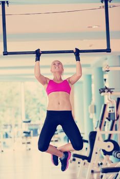 healthy lifestile, young woman in fitness gym lifting on bar and working on her back and hands muscles