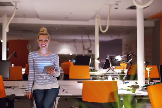 young female entrepreneur working on digital tablet in night office