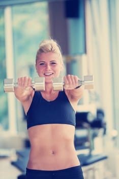 Gorgeou woman girl lifting some weights and working on her biceps in a gym