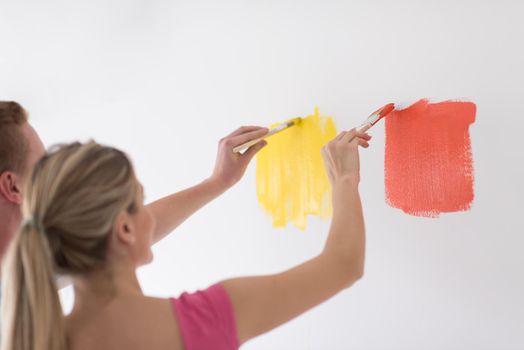 happy smiling young couple painting interior wall of new house