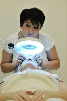 Young beautiful woman receiving cosmetic facial mask in spa beauty salon and relax