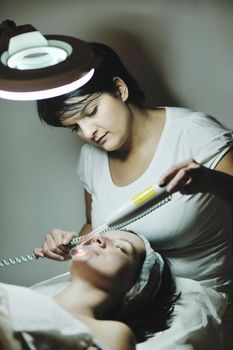 Young beautiful woman receiving cosmetic facial mask in spa beauty salon and relax