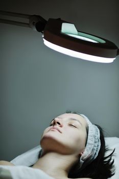 Young beautiful woman receiving cosmetic facial mask in spa beauty salon and relax