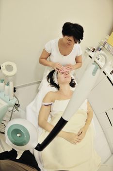 Young beautiful woman receiving cosmetic facial mask in spa beauty salon and relax