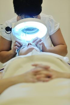 Young beautiful woman receiving cosmetic facial mask in spa beauty salon and relax