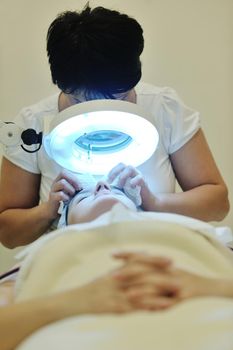 Young beautiful woman receiving cosmetic facial mask in spa beauty salon and relax