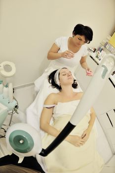 Young beautiful woman receiving cosmetic facial mask in spa beauty salon and relax