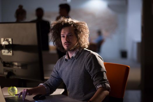 Young man working on computer at night in dark office. The designer works in the later time.