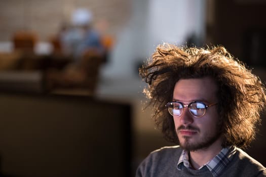 Young man working on computer at night in dark office. The designer works in the later time.