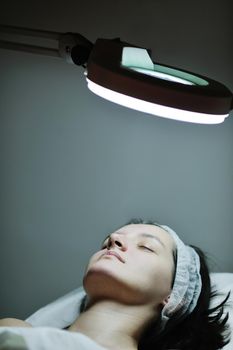 Young beautiful woman receiving cosmetic facial mask in spa beauty salon and relax