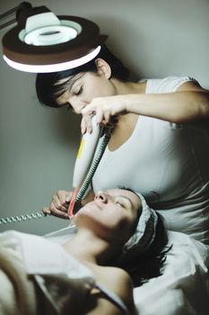 Young beautiful woman receiving cosmetic facial mask in spa beauty salon and relax