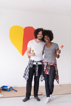 Portrait of loving multiethnict couple with painted heart on wall