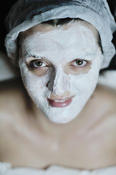 Young beautiful woman receiving cosmetic facial mask in spa beauty salon and relax