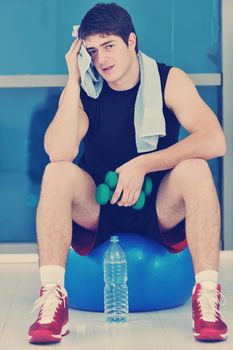 young man in fintess sport club exercise withweights and relaxing