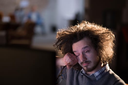 Young man working on computer at night in dark office. The designer works in the later time.