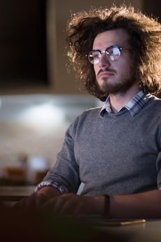 Young man working on computer at night in dark office. The designer works in the later time.