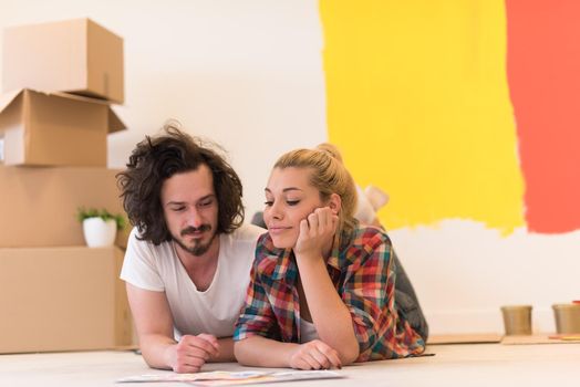 Happy young couple relaxing after painting a room in their new house on the floor