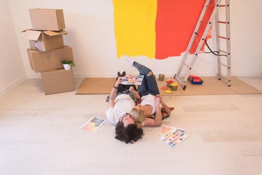 Happy young couple relaxing after painting a room in their new house on the floor