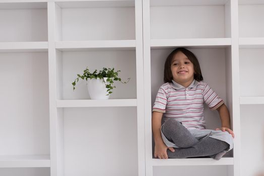 happy young boy having fun while posing on a shelf in a new modern home