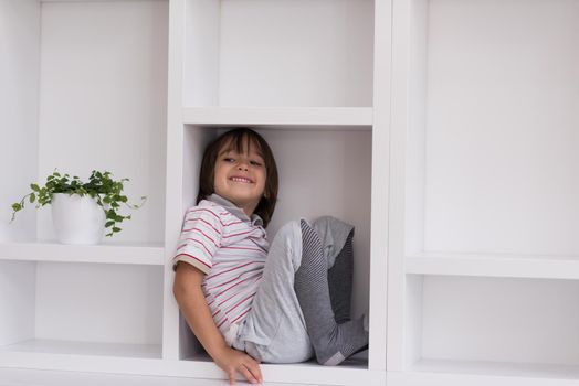 happy young boy having fun while posing on a shelf in a new modern home