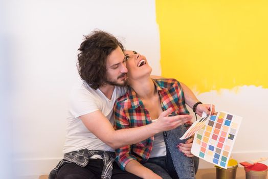 Happy young couple relaxing after painting a room in their new house on the floor