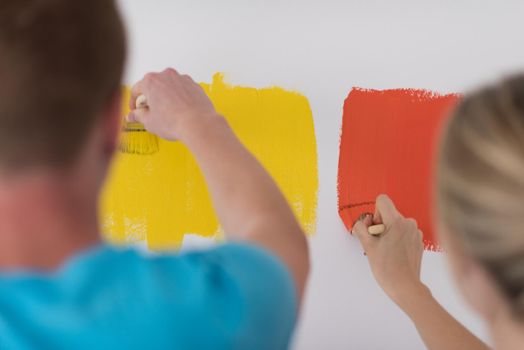 happy smiling young couple painting interior wall of new house