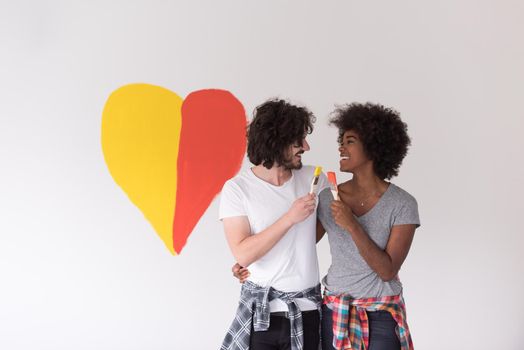 Portrait of loving multiethnict couple with painted heart on wall