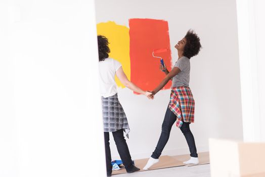 happy young multiethnic couple painting interior wall of new house