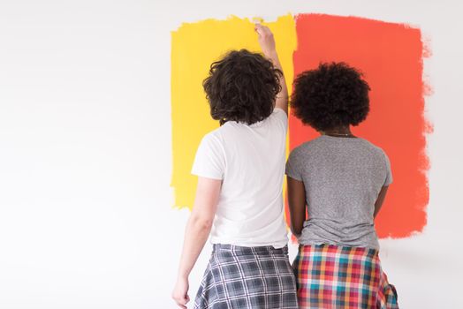 happy young multiethnic couple painting interior wall of new house