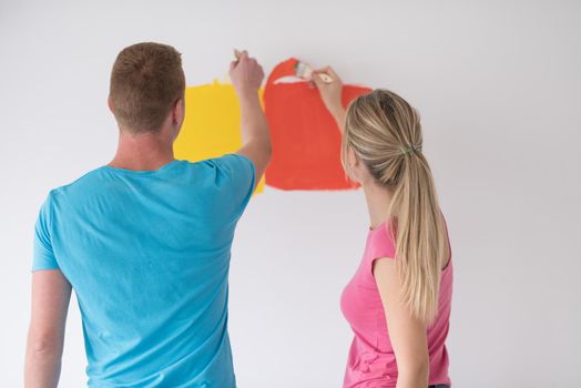 happy smiling young couple painting interior wall of new house