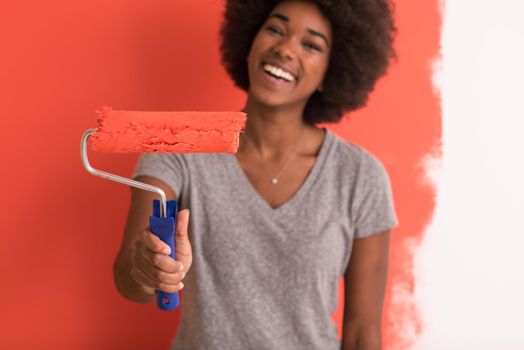 portrait of a young beautiful African American woman painting wall in her new apartment