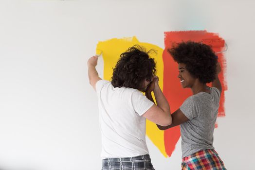 happy young multiethnic couple painting interior wall of new house