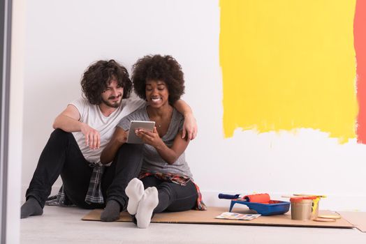 Happy young multiethnic couple relaxing after painting a room in their new house on the floor