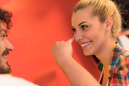 happy smiling young couple painting interior wall of new house